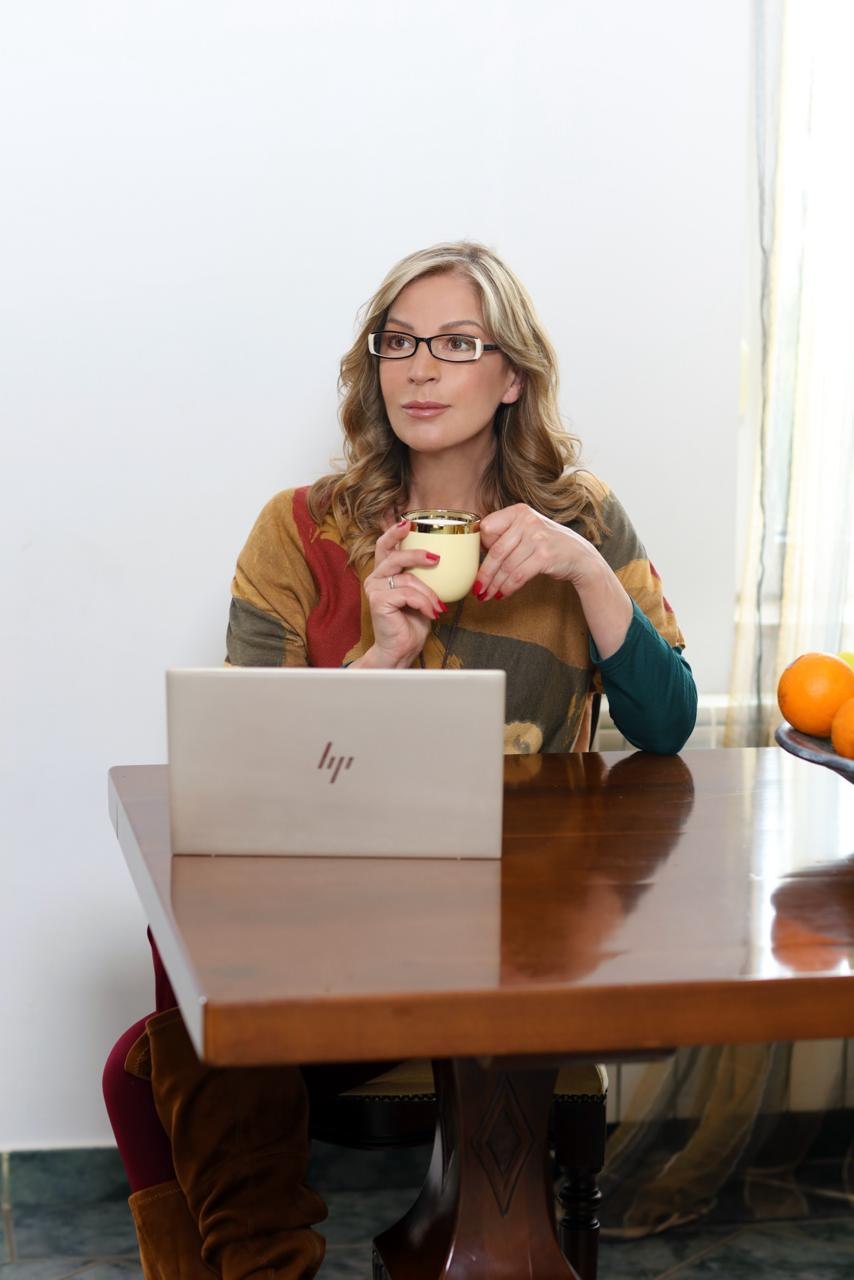 Ivana Kuzmanović zamišljeno gleda u stranu uz laptop i šolju