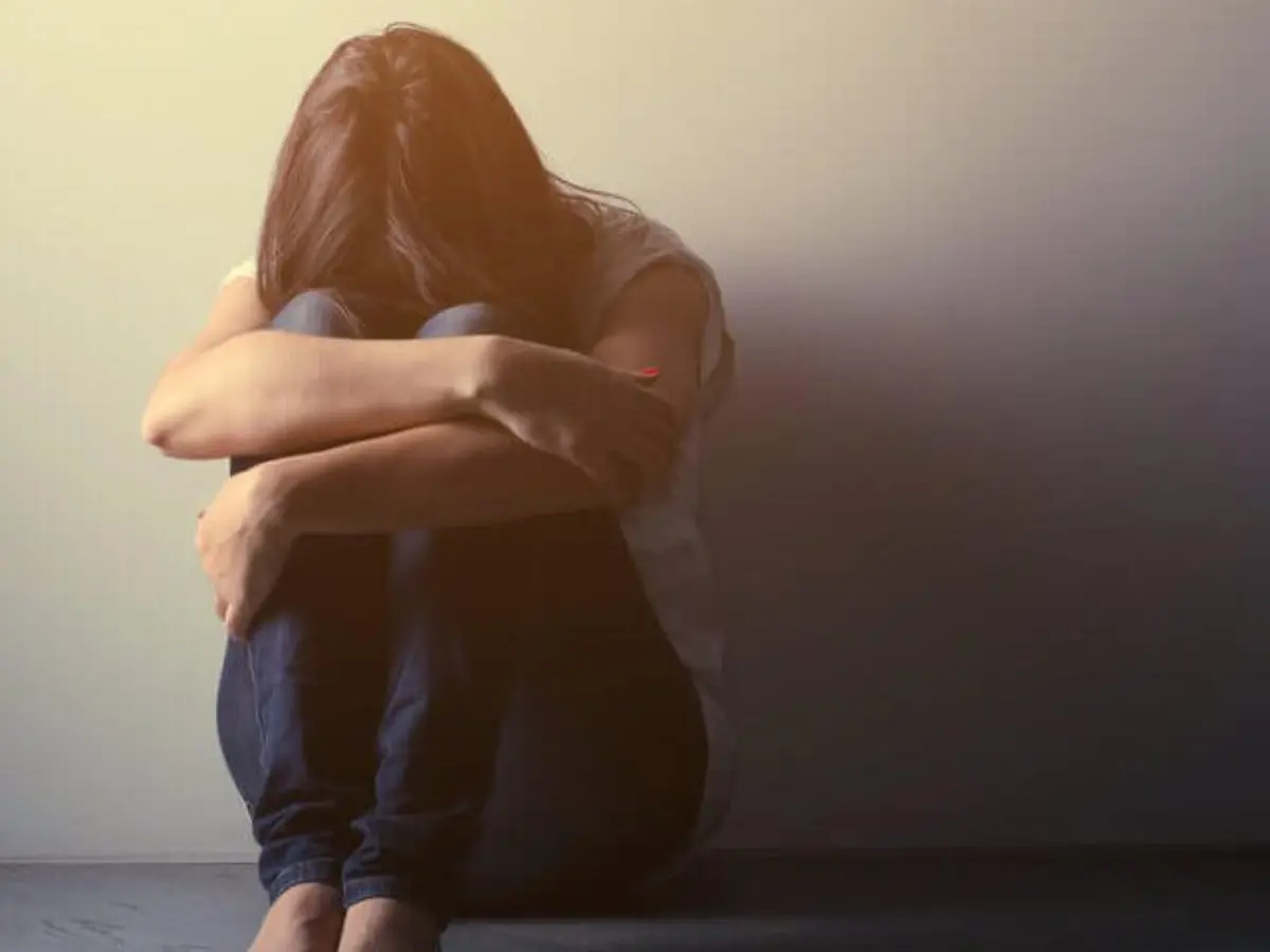 Žena sedi sama uz zid sa glavom savijena – ljubavna patnja i emocionalni bol
